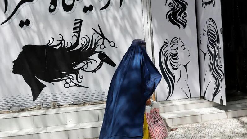 Mulher afegã passa por um salão de beleza em Cabul