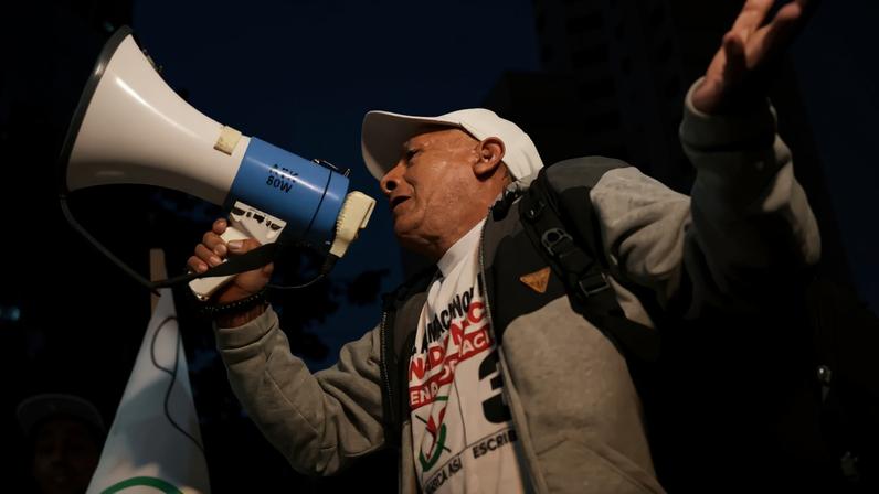 Uma apoiadora do candidato de esquerda à Presidência do Peru, Roberto Sánchez, usa um megafone enquanto simpatizantes do político se reúnem em frente ao Júri Nacional de Eleições (JNE), durante a continuidade da apuração dos votos do segundo turno presidencial entre Sánchez e a candidata conservadora Keiko Fujimori, em Lima, Peru, em 9 de junho de 2026. REUTERS/Stifs Paucca.