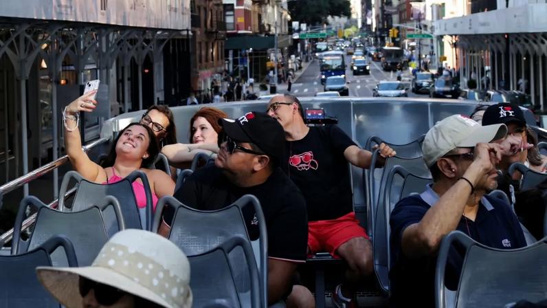 Um turista tira uma selfie em grupo no "Big Bus" na Times Square, em Nova York, EUA, em 27 de agosto de 2024. (Foto: Reuters/Kent J Edwards)