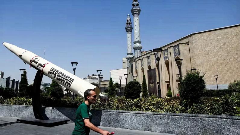 Um homem caminha ao lado de uma réplica simbólica de um míssil iraniano , em uma rua de Teerã, Irã, em 11 de junho de 2026
