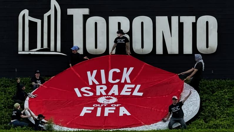 Manifestantes seguram faixa onde se lê "Expulsem Israel da Fifa", em Toronto, Ontário, Canadá