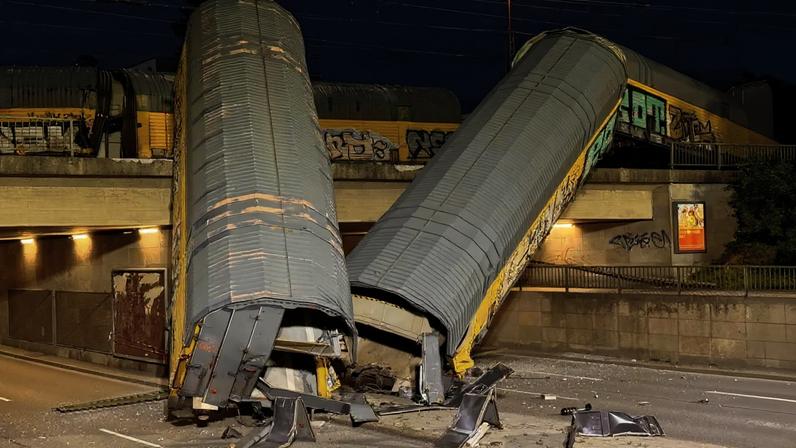Dois vagões de um trem de carga que descarrilou após uma colisão caíram de uma ponte e ficaram parados em uma rua em Munique, Alemanha, em 20 de junho de 2026. REUTERS/Christine Uyanik
