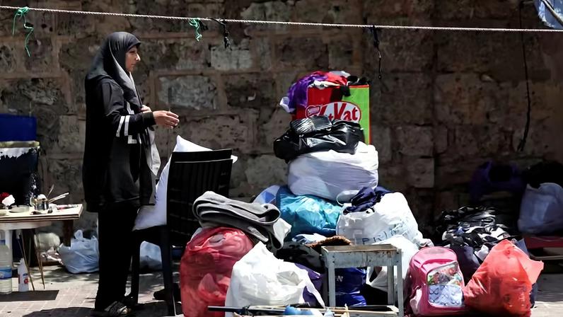 Uma mulher está perto de seus pertences em uma calçada em Beirute , onde ela e sua família têm vivido em uma tenda, enquanto se prepara para retornar para casa após um acordo provisório entre os EUA e o Irã, em Beirute , Líbano, 24 de junho de 2026 — Foto: REUTERS/Khalil Ashawi