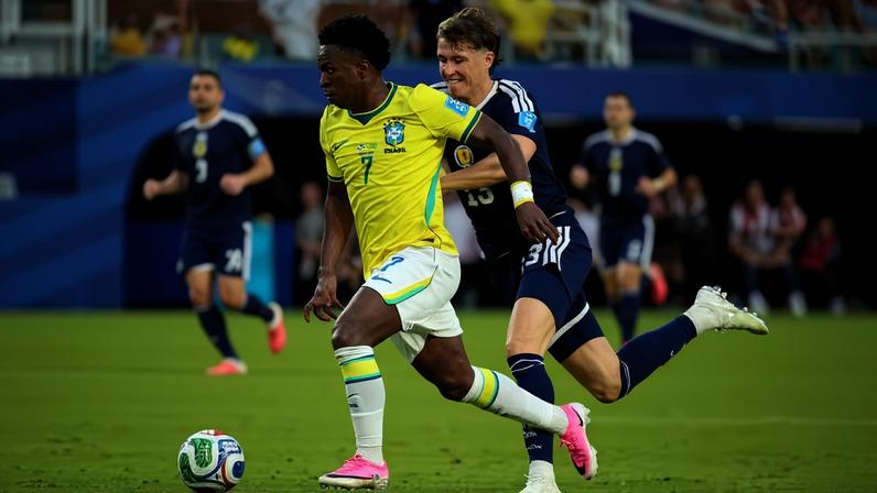 O atacante Vini Jr., da seleção brasileira, dribla o zagueiro escocês Jack Hendry, em jogo pela fase de grupos da Copa do Mundo 2026, em Miami, Flórida; lance deu origem a gol que foi anulado pela arbitragem, justificando que o brasileiro cometeu falta de ataque no defensor da Escócia