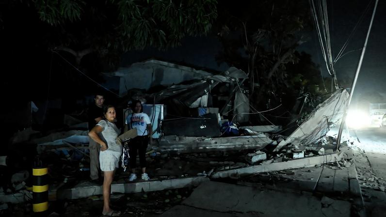 People stand next to a destroyed building after earthquakes, in La Guaira, Venezuela, June 25, 2026. REUTERS/Maxwell Briceno