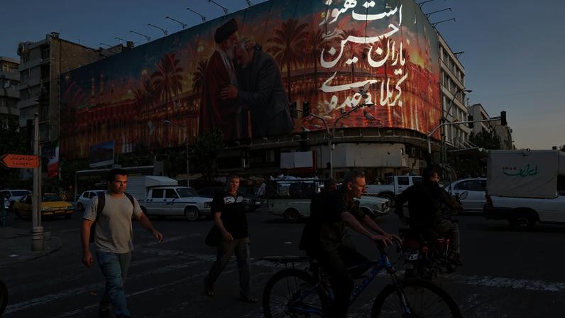 Pessoas passam diante de um painel com uma imagem que retrata o falecido líder supremo do Irã, aiatolá Ali Khamenei, abraçando o falecido comandante militar iraniano, Qassem Soleimani, em Teerã — Foto: Majid Asgaripour/WANA via Reuters