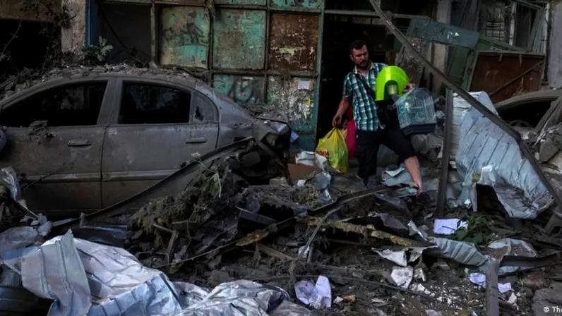 Morador de Kiev carrega alguns pertences em meio à destruição causada por um ataque russo
