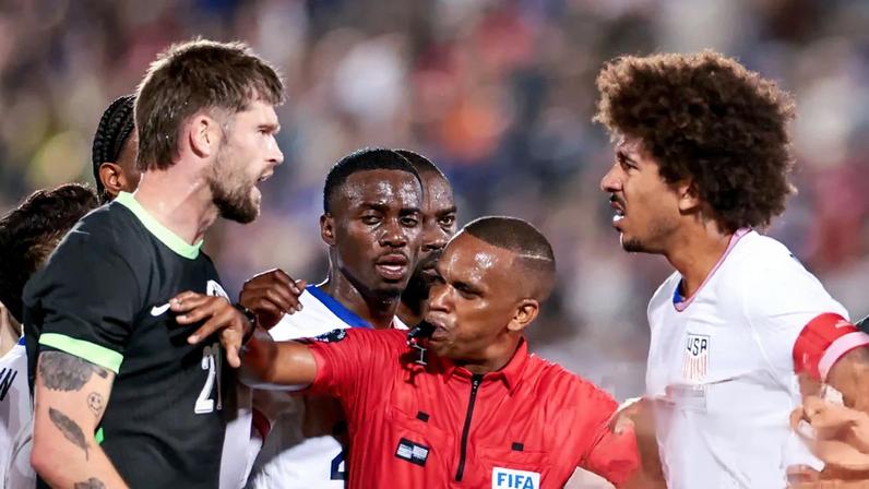 Referee Kwinsi Williams gestures between players from two teams during a heated moment on a soccer field
