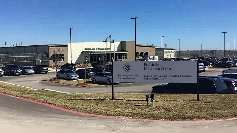 An exterior view of the Prairieland Detention Center in Alvarado, Texas, showing its signage and cars parked in a car park.