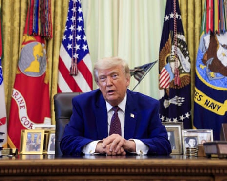 Donald Trump sits at the Resolute Desk in the Oval Office