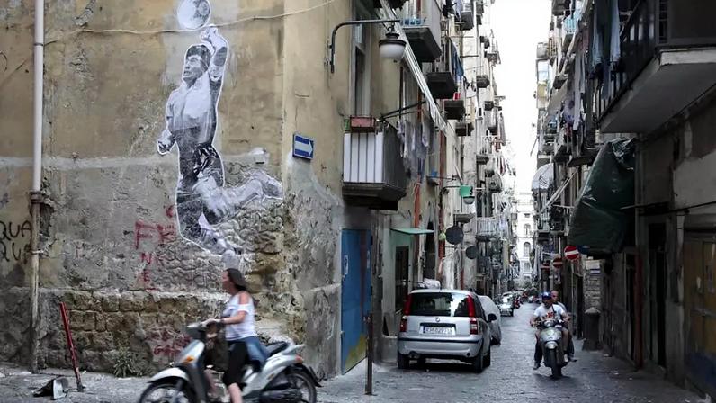 Um mural do artista plástico argentino Spiga eterniza o momento do gol de mão de Maradona na Copa de 1986 - um dos muitos que se espalham pelas ruas de Nápoles, cidade em que o craque jogou e se tornou ídolo. Alessio Paduano/Anadolu Agency/Getty Images