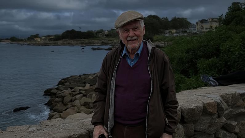 Submitted photo Arthur Rose stands in front of the ocean, wearing a purple sweater, brown jacket and cap