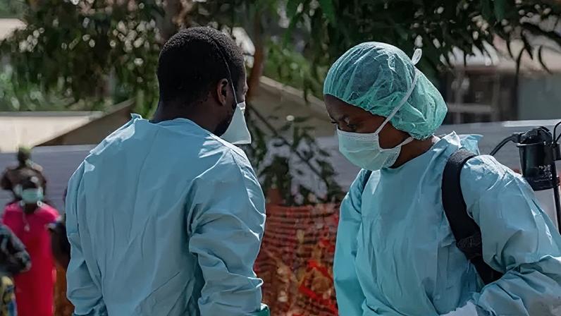 Anadolu via Getty Images Two health workers are pictured wearing blue protective gear