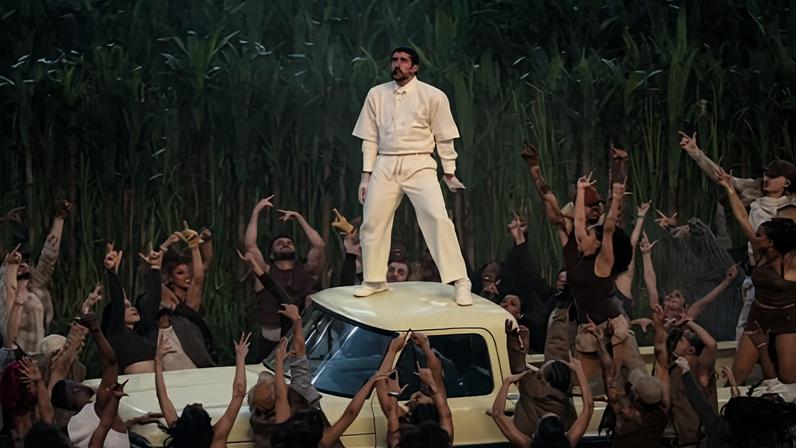 Bad Bunny on the roof of a flatbed truck surrounded by people
