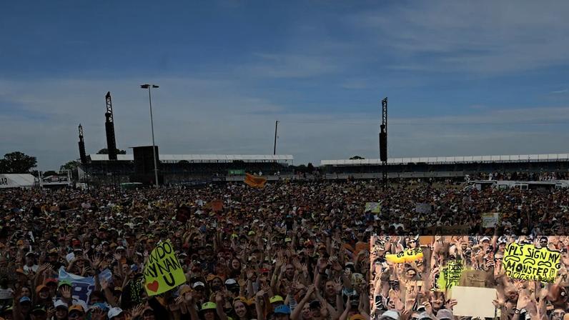 Fans on the track look up at Lewis Hamilton after he won the 2024 British Grand Prix.