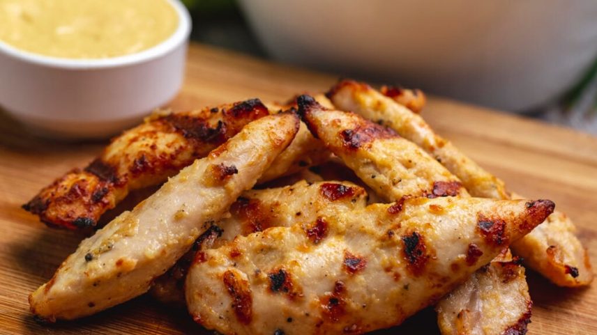 grilled chicken breast on wooden board side view