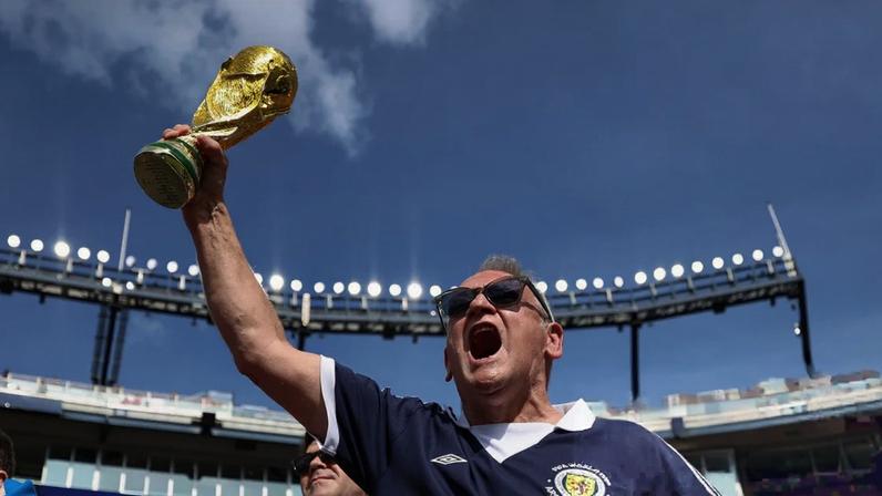 A Scotland fan raises a World Cup trophy above his head in a stadium