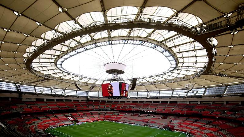Empty BC Place Vancouver with red seats, green football pitch, and distinctive curved roof with circular skylight