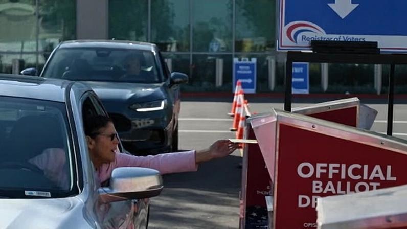 A voter drops her mail-in ballot in San Diego in November 2025.