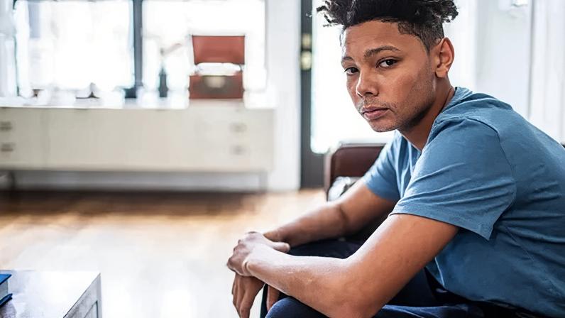Getty Images An anxious-looking teenager sits in a room, looking at the camera.