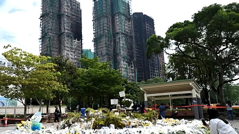A woman looks at flowers laid for the victims of a deadly fire at the Wang Fuk Court residential estate in Tai Po district of Hong Kong.