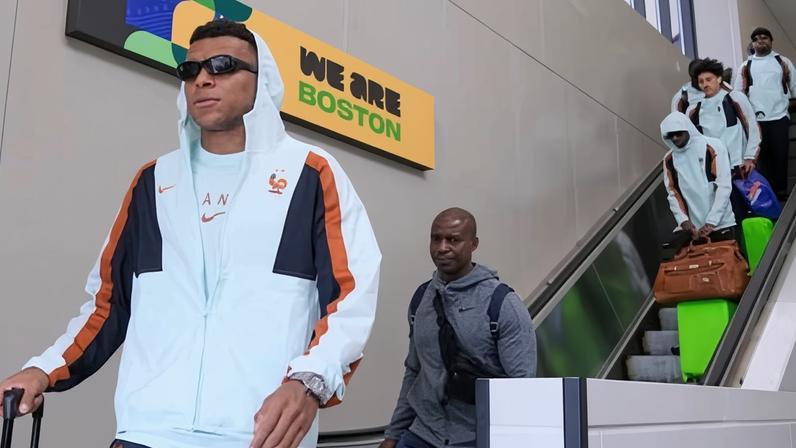 Kylian Mbappé arrives at Boston's Logan airport with France teammates on an escalator behind him