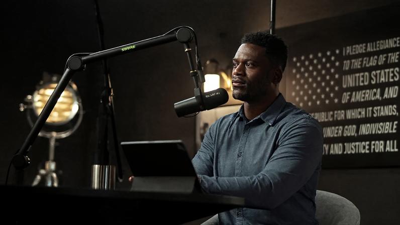 A photo of Benjamin Watson at mic with the title of the podcast The Just Life overlaid on the image