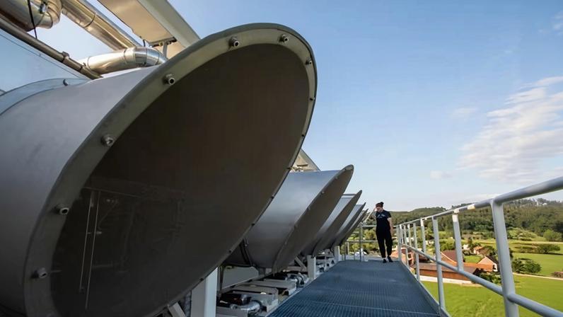 Direct air capture fans mounted on a rooftop walkway against a clear sky