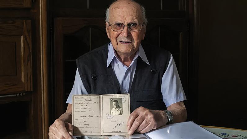 Albert Corrieri, então com 102 anos, mostra seu caderno de prisioneiro, o “vorläufiger Fremdenpass”, em seu apartamento em Marselha, no sudeste da França, em 21 de junho de 2024