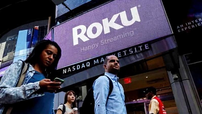 People pass by a video sign display with the logo for Roku Inc in New York in 2017.