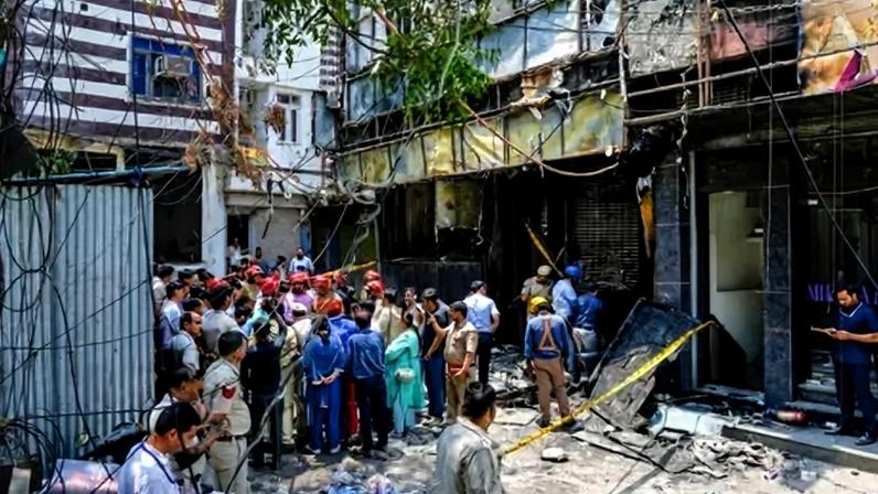 Firefighters and police officers stand at the site after the fire in Delhi