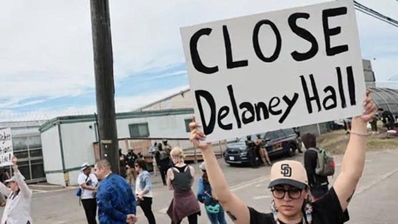 Protesters hold signs as ICE agents stand guard outside Delaney Hall on 27 May in Newark, New Jersey.