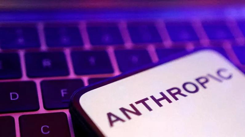 Uma tela de smartphone mostrando o logotipo da Anthropic em letras pretas em um fundo todo branco, colocado em um teclado de laptop iluminado em rosa e roxo