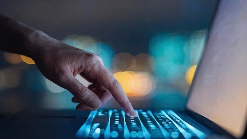Close up of woman's hand typing on computer keyboard in the dark