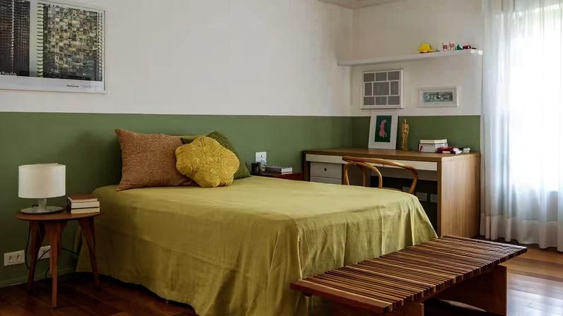 O quarto ganha frescor com a meia parede pintada com a cor Babosa, da Suvinil. Mesa de cabeceira Rodésia, de Paulo Alves, que desenhou também o banco Íris