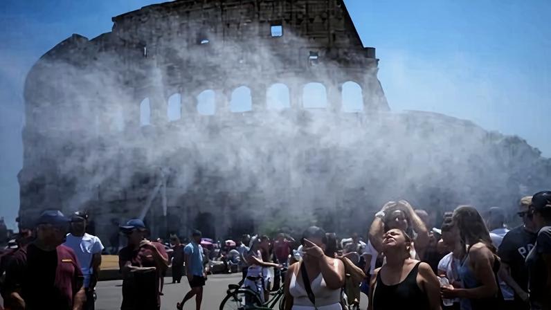 People gather under a water-sprinkling cannon while visiting the Colosseum in Rome.