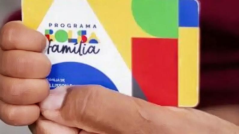 Pessoa segurando cartão do Bolsa Família.