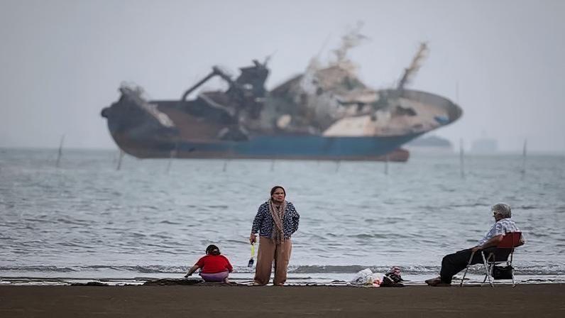 Pessoas se reúnem em uma praia, enquanto um navio no Estreito de Ormuz é visível, perto da praia de Bandar Abbas, no Irã, em 31 de maio de 2026. Amirhosein Khorgooi/ISNA/WANA (Agência de Notícias da Ásia Ocidental) via REUTERS