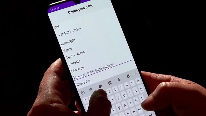 Mãos digitando chave Pix em smartphone com tela de dados bancários