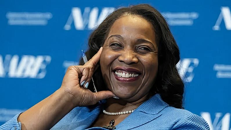 Lisa D. Cook, a member of the Board of Governors of the Federal Reserve, smiles while holding her hand against her face. She is wearing a blue suit and speaks at The Capital Hilton during the 42nd annual National Association for Business Economics Economic Policy Conference on February 24, 2026 in Washington, DC.
