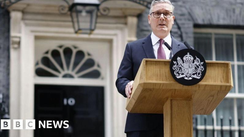 Sir Keir Starmer - a man wearing a dark suit and red tie - stands at a lectern with the government crest on it outside No 10 Downing Street