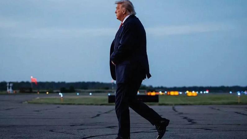 Donald Trump após descer de seu avião, andando na pista de um aeroporto