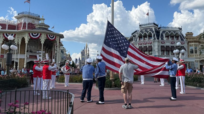 Magic Kingdom security's honor guard lowers the flag as part of its daily flag retreat as guests look on.