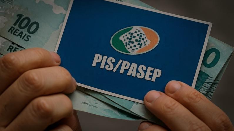Pessoa com cartão do PIS/Pasep e dinheiro do abono.
