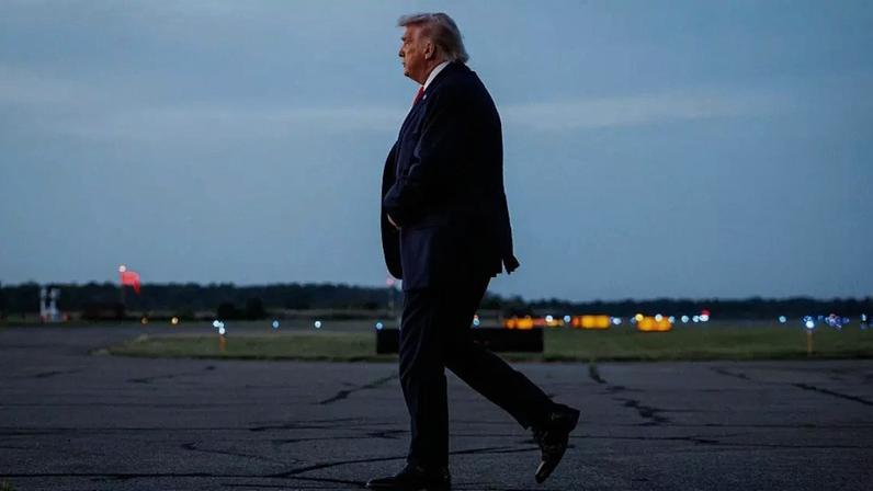 Donald Trump após descer de seu avião, andando na pista de um aeroporto