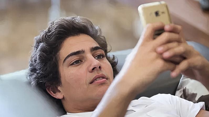 Getty Images A young man lying on the sofa looking at his phone