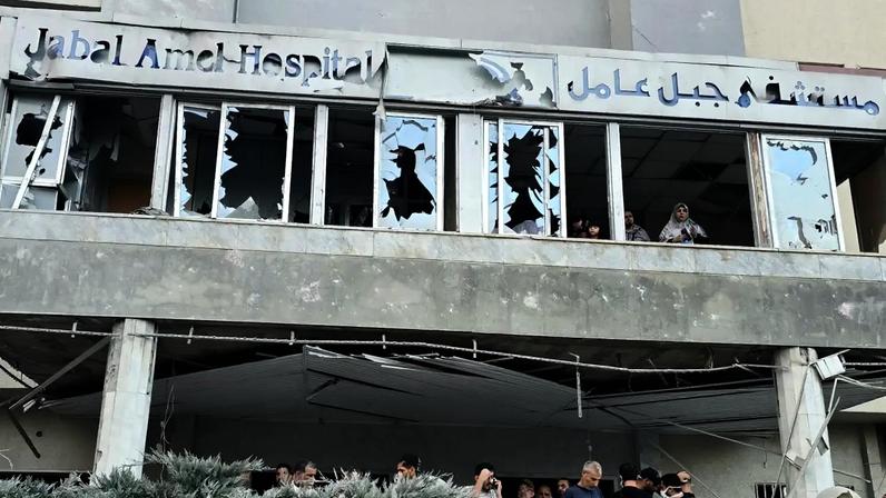 Pessoas se reúnem enquanto outras observam através das janelas danificadas do hospital, no local de um ataque israelense que atingiu as proximidades do hospital na cidade de Tiro, no sul do Líbano, em 1º de junho de 2026