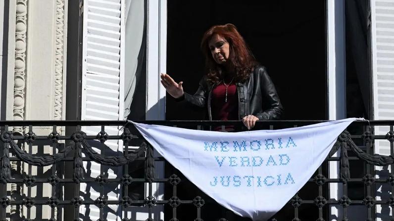 A ex-presidente argentina Cristina Fernández de Kirchner - que está cumprindo prisão domiciliar - gesticula da sacada enquanto o cortejo fúnebre de Taty Almeida, a falecida presidente da associação de direitos humanos Madres de Plaza de Mayo, passa em frente à sua casa a caminho do enterro, em Buenos Aires. 16/06/2026 - (Luis Robayo/AFP)