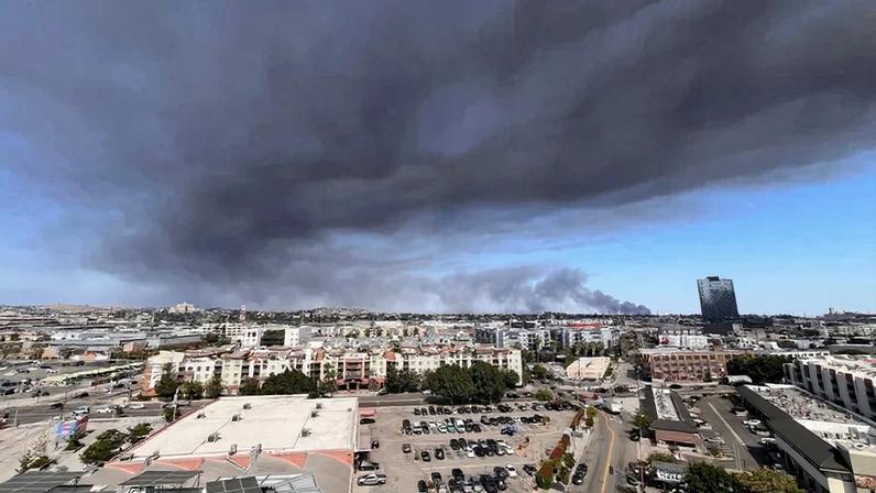 Fumaça negra sobe de um incêndio em um armazém em Boyle Heights, visto do centro de Los Angeles, em 17 de junho de 2026 (AFP)
