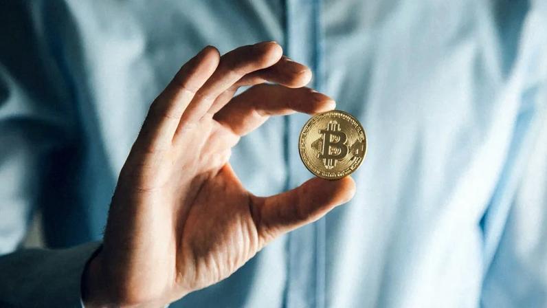 Homem segurando moeda de bitcoin